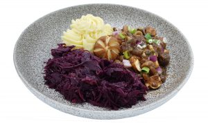 Vegetarische hachee op een bord met rode kool en aardappelpuree